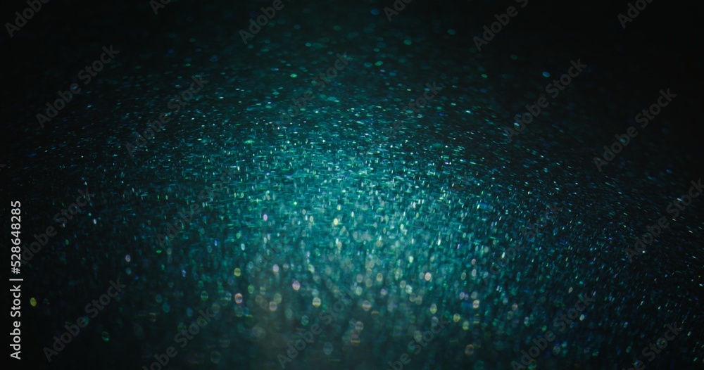 Blur sparkles background. Glitter particles. Shimmering bokeh glow. Defocused blue green color grain glare on dark black abstract poster. Blur sparkles background. Glitter particles. Shimmering bokeh glow. Defocused blue green color grain glare on dark black abstract poster.