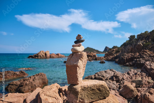 Stones accumulated in balance in the little beach of Su Sirboni has red surfacing rocks - Sardinia - italy