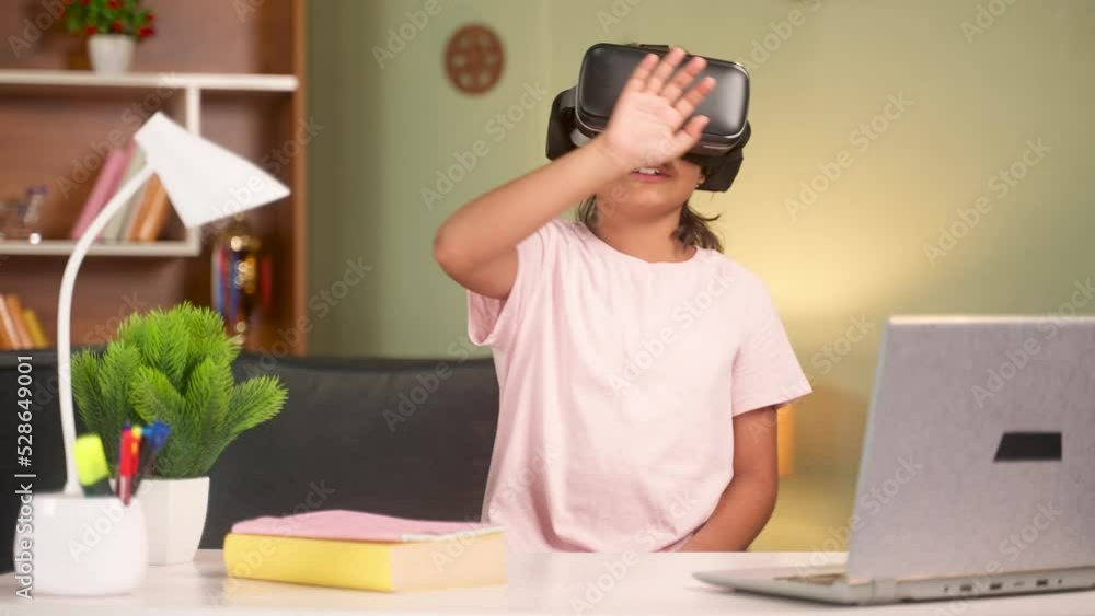 Girl kid with vr or virtual reality headset during online class interacting by experiencing object from metaverse iat home - conecept of modern education, learning and technology Girl kid with vr or virtual reality headset during online class interacting by experiencing object from metaverse iat home - conecept of modern education, learning and technology