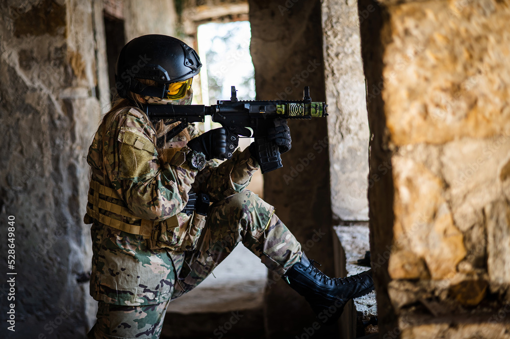 Fototapeta premium A woman in an army uniform shoots a firearm in an abandoned building. 