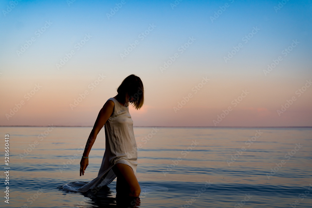 A girl swims in the river at sunset