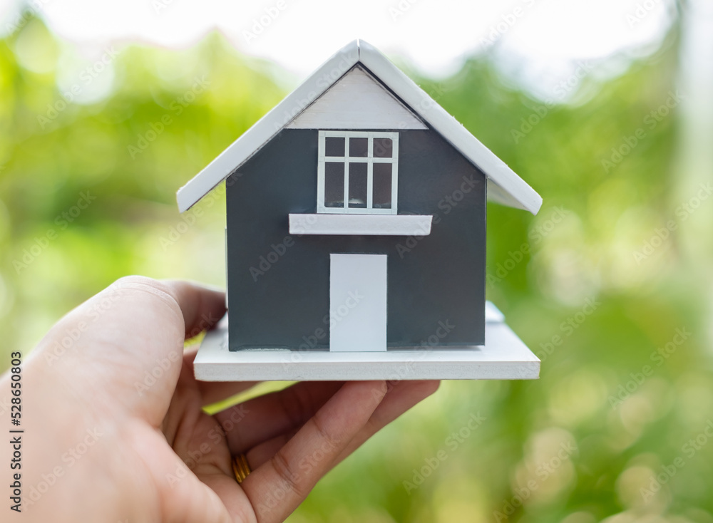 Home insurance concept. hand holding model home with green nature background and copy space Home insurance concept. hand holding model home with green nature background and copy space