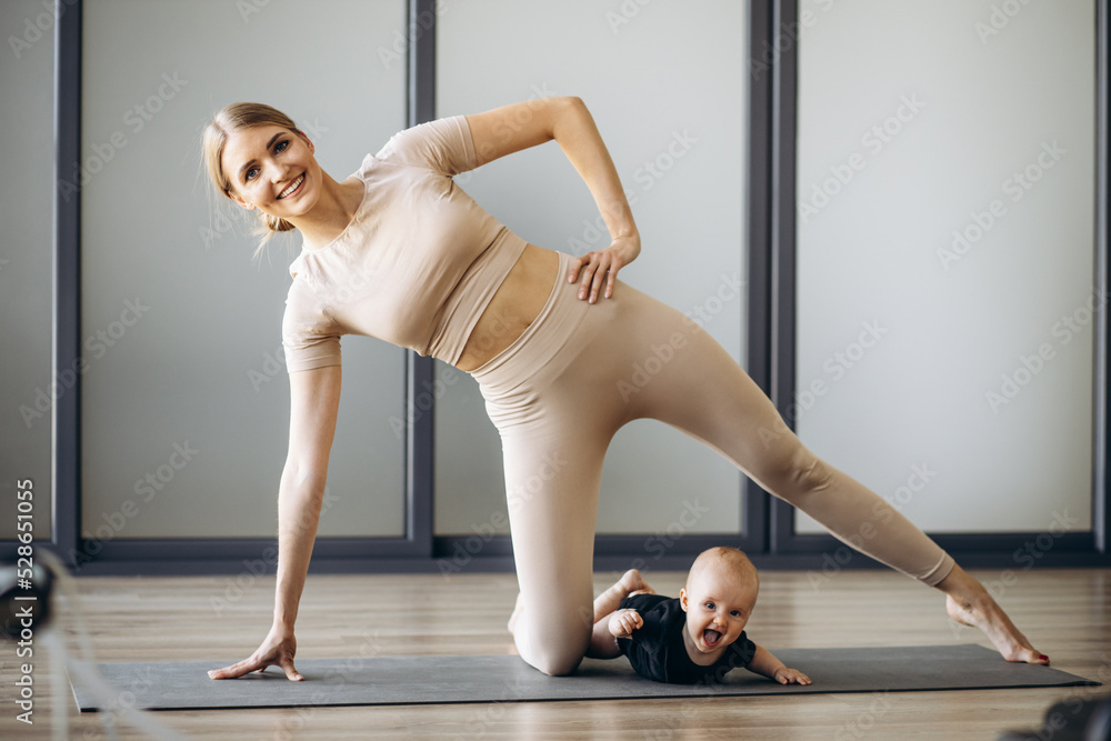 Mother with toddler daughter exercising on mat