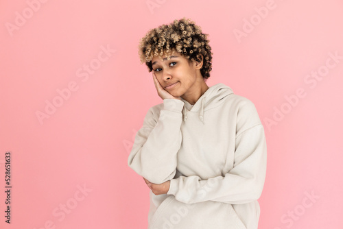 Tired African American woman in studio. Female model with curly hair looking uninterested. Portrait, studio shot, emotion concept