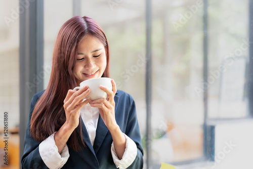 Portrait asian girl drinking and enjoying coffee at her office.