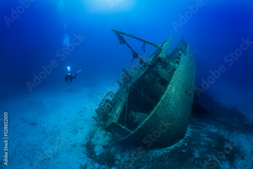 A scuba diver explores a sunken shipwreck at the bottom of the mediterranean sea, Greece © moofushi