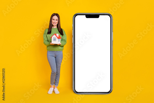 Full length body size view of attractive cheery girl holding house copy space ad isolated on bright yellow color background