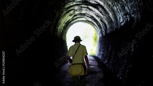 A lonely man walking in a tunnel.