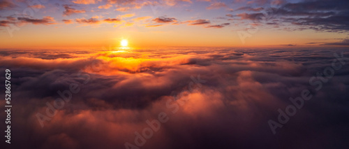 Fototapeta Naklejka Na Ścianę i Meble -  Majestic photo above the clouds of setting sun under horizon. Vibrant colours of burning clouds lit by last sun rays
