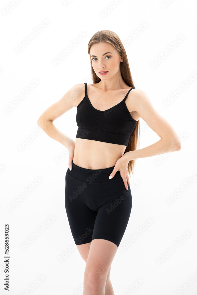 Slim sporty fitness young woman gymnast in sportswear training performs exercises on a white background Slim sporty fitness young woman gymnast in sportswear training performs exercises on a white background