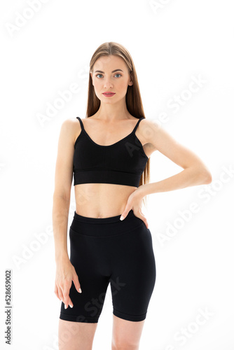Slim sporty fitness young woman gymnast in sportswear training performs exercises on a white background