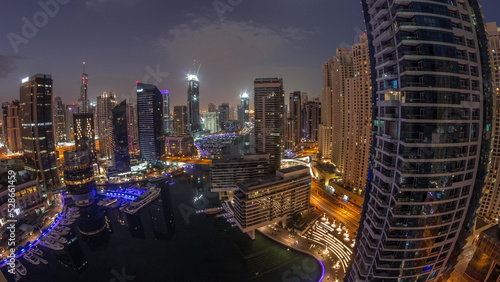 Aerial view to Dubai marina skyscrapers around canal with floating boats night to day timelapse