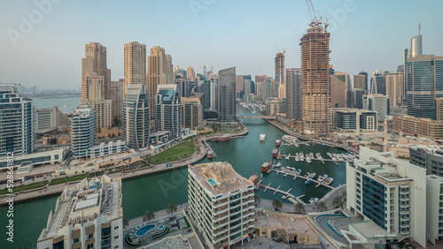 Panorama showing Dubai Marina with several boat and yachts parked in harbor and skyscrapers around canal aerial timelapse.