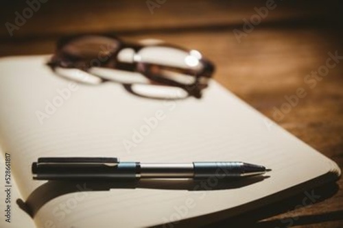 Eyeglasses and pen on book at desk