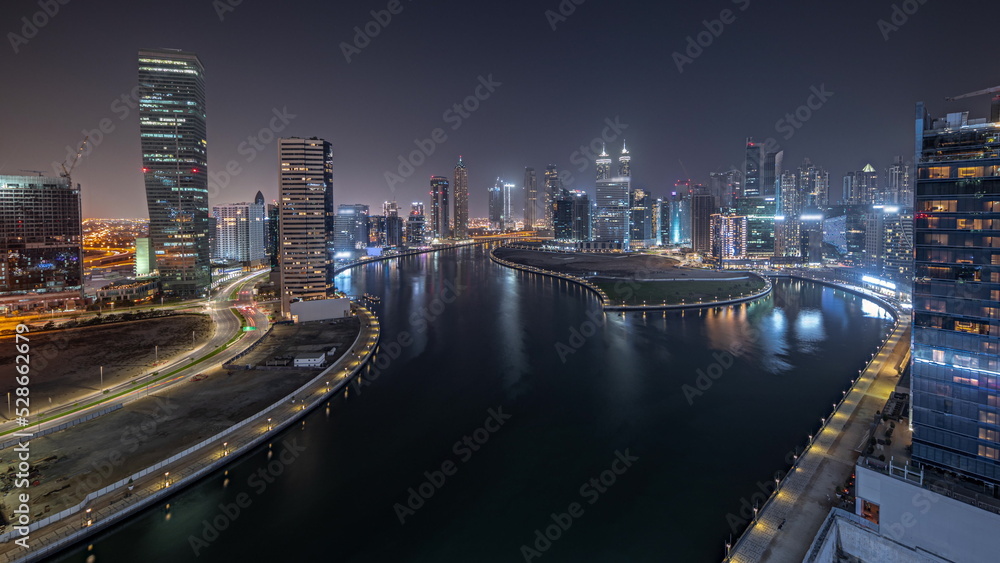Panorama showing cityscape of skyscrapers in Dubai Business Bay with water canal aerial night timelapse