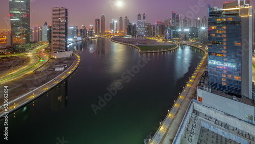 Cityscape of skyscrapers in Dubai Business Bay with water canal aerial night to day timelapse