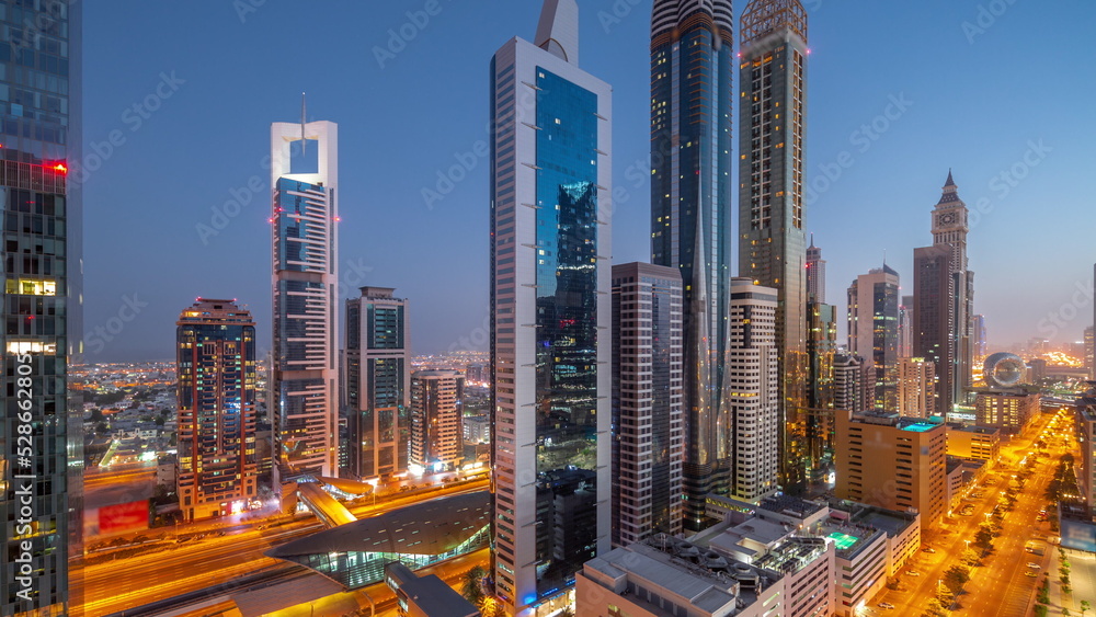 Fototapeta premium Aerial view of Dubai International Financial District with many skyscrapers night to day timelapse.