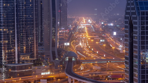 Busy Sheikh Zayed Road aerial night to day timelapse, metro railway and modern skyscrapers around in luxury Dubai city.