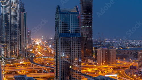 Dubai city skyline panoramic view with metro and cars moving on city s busiest highway aerial night to day timelapse