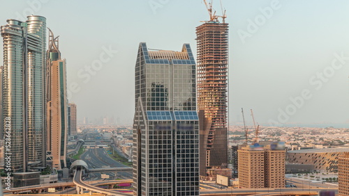 Dubai city skyline panoramic view with metro and cars moving on city's busiest highway aerial morning timelapse
