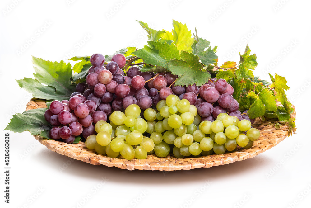 Clusters of white and pink grapes on a wicker dish. isolate on white background
