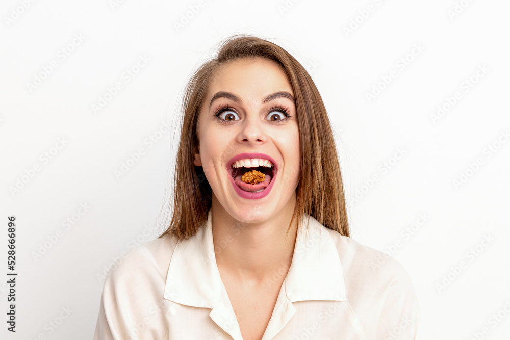 Happy young caucasian woman eating walnuts with an open mouth on white background with copy space Happy young caucasian woman eating walnuts with an open mouth on white background with copy space