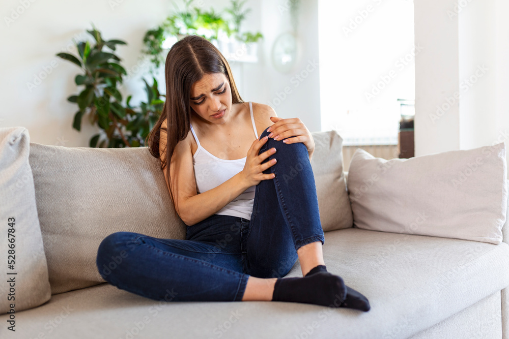 woman holding the knee with pain on sofa,health care and medical concept.