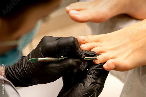 Professional pedicure. Process of cuticle removal on female toes in spa salon. Concept of beauty