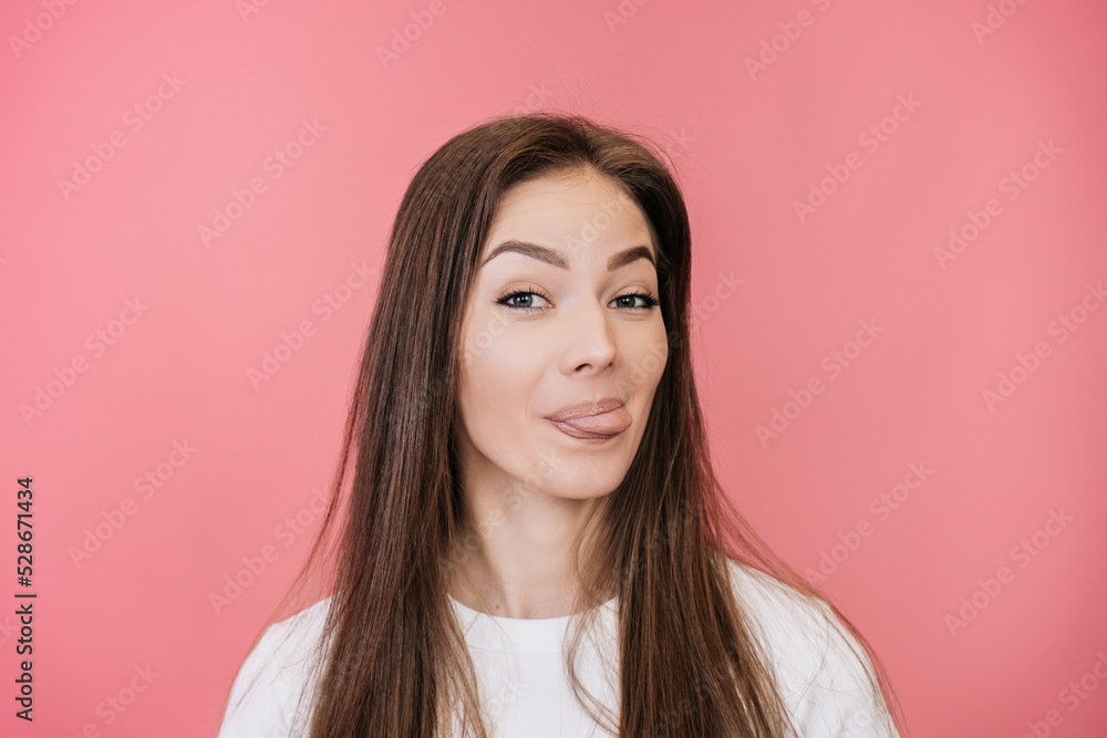 Don’t worry, be happy! Close up of attractive young woman with loose hair showing tongue, having fun against pink background. Happy people concept. Let’s play. Cheerful Italian female ready for rest. Don’t worry, be happy! Close up of attractive young woman with loose hair showing tongue, having fun against pink background. Happy people concept. Let’s play. Cheerful Italian female ready for rest.