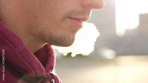 Young man smoke vape pod system outdoors. Male inhales and exhales vapor of electronic cigarette.