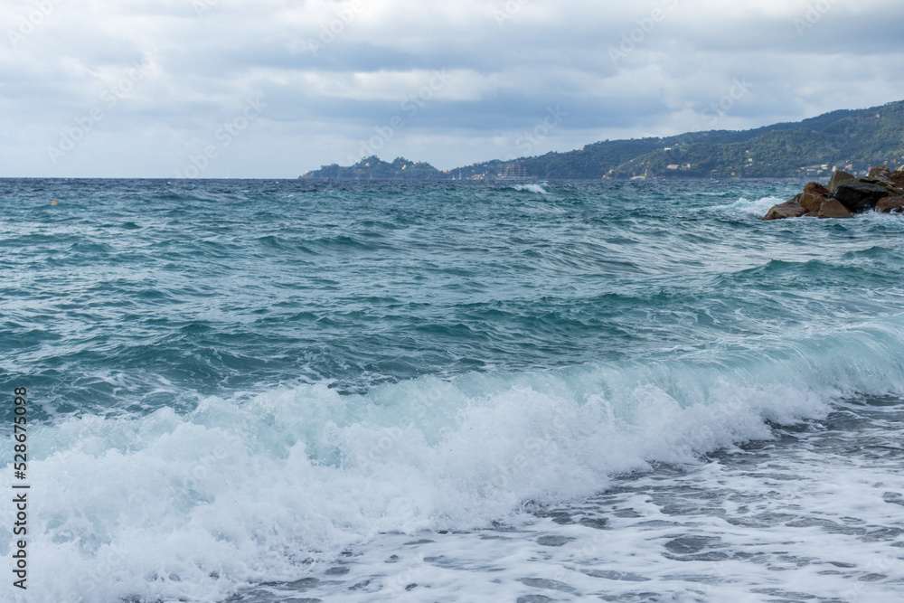 Rough sea and clouds in Tigullio Gulf, Italy. On the background the promontory of Portofino. Copy space.