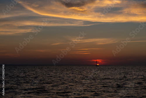 smutna żaglówka na tle zachodzącego nad Bałtykiem słońca