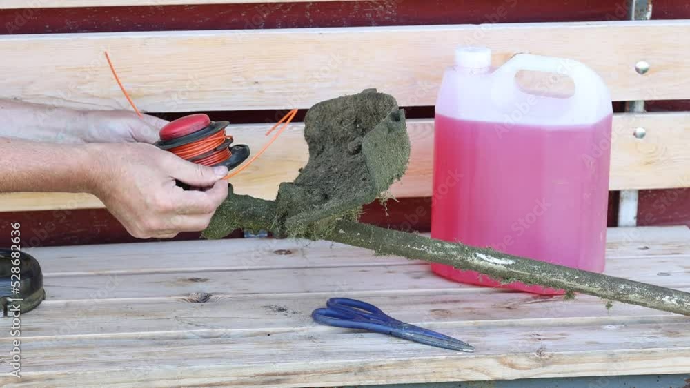 Adjusting of string trimmer for destruction of weeds, installation of spool with line. Stock