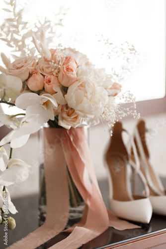 The bride's wedding bouquet of roses and orchids and the bride's shoes
