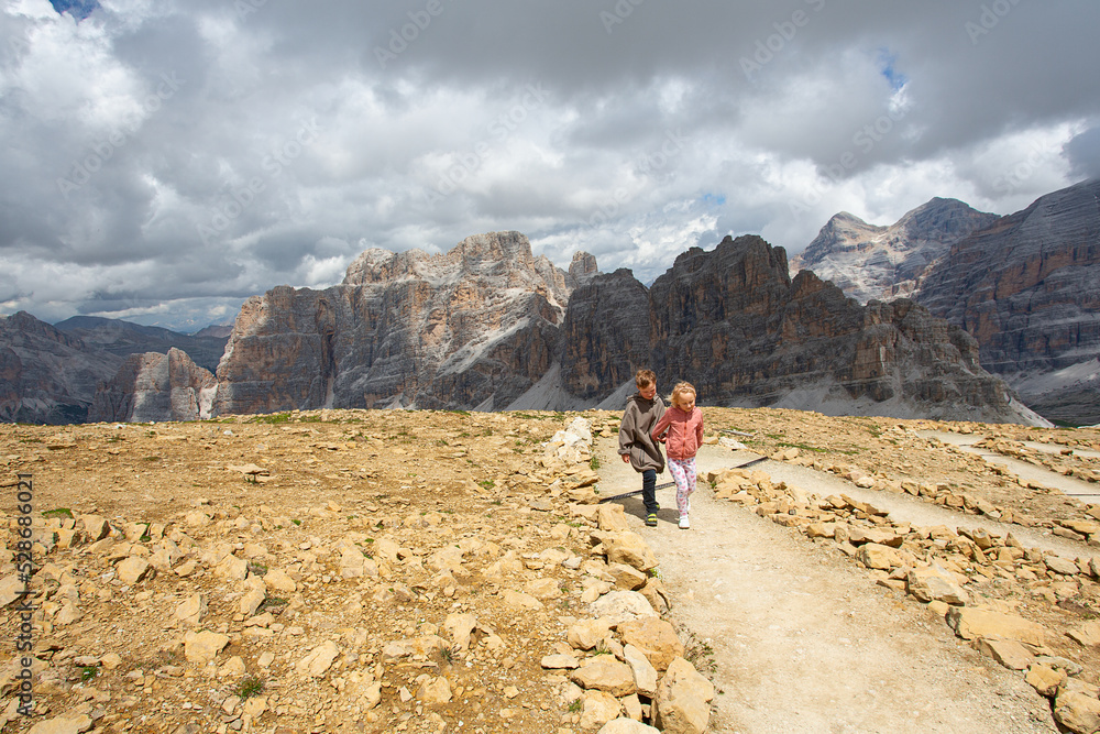 Cute kids are walking in mountain area. Traveling in Italian Dolomites with kids.