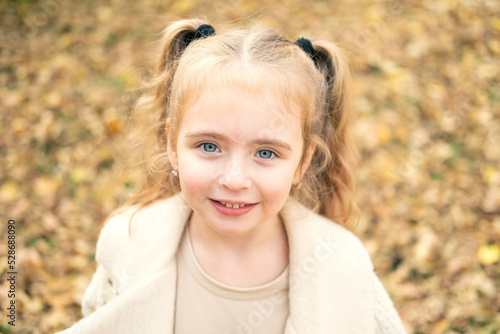 portrait of smiling beautiful little girl in stylish clothes in nature in autumn park