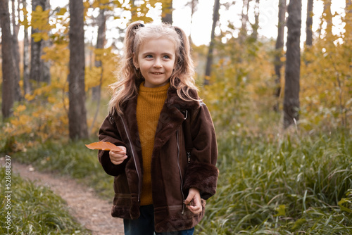 Happy little child girl smiling, holding autumn leaves, having fun in the fall forest © Юля Шевцова