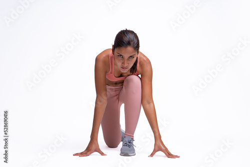 Full body length shot of smiling young sporty Asian woman fitness model in pink sportswear posting runner at a low start position. isolated on white background. Fitness and healthy lifestyle concept.