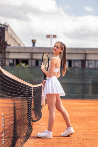 Concept of professional sport healthy lifestyle attractive tennis player young lady holding the racket in hands and smiling cute posing to the camera