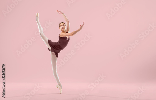 Fototapeta Naklejka Na Ścianę i Meble -  Beautiful young ballerina on a white background. The ballerina is dressed in a red leotard, pink leotards, pointe shoes.