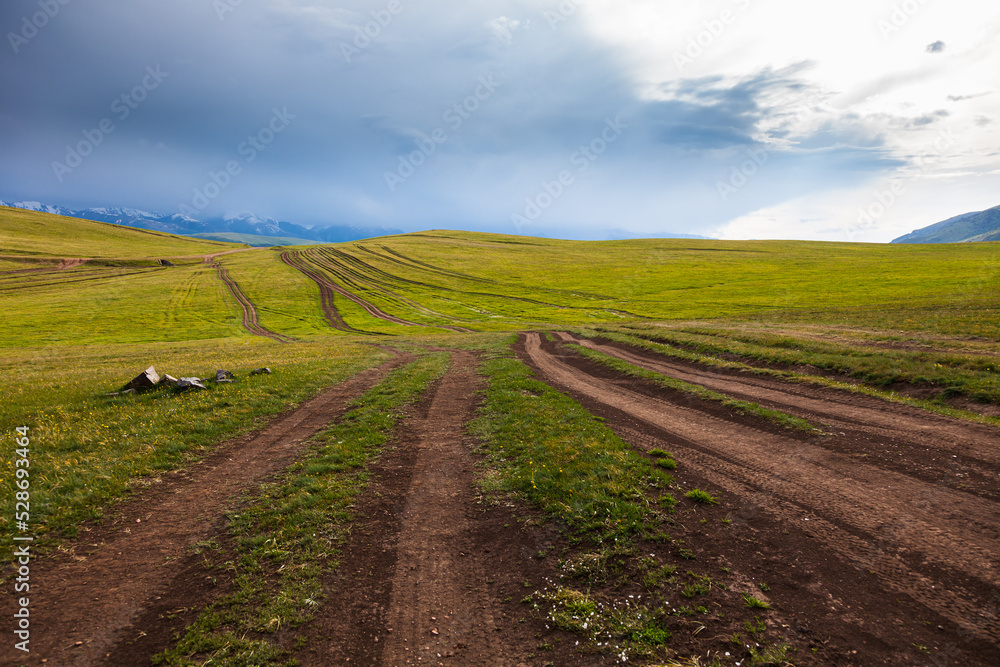 A bunch of winding roads among the green hills in the valley of the charming plateau of Assy under thunderclouds