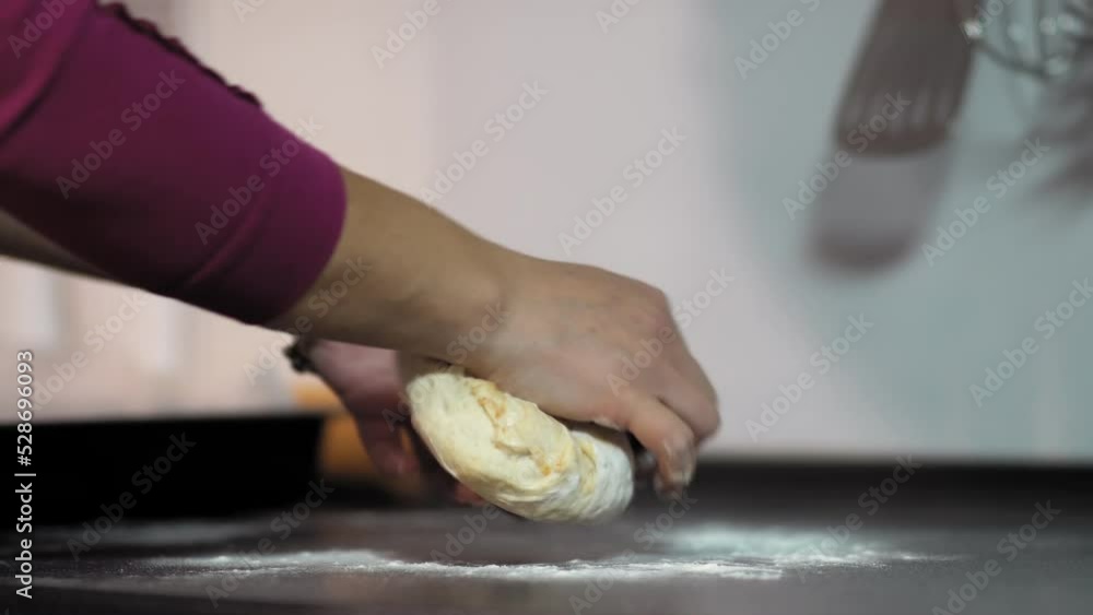 Women's hands rolling the dough on the kitchen table with flour Women's hands rolling the dough on the kitchen table with flour