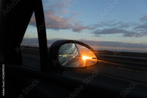 Sunset in the car mirror.Concept of travelling by car .