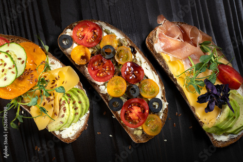 Delicious open sandwiches with avocado, cheese,bacon,cherry tomato and olive