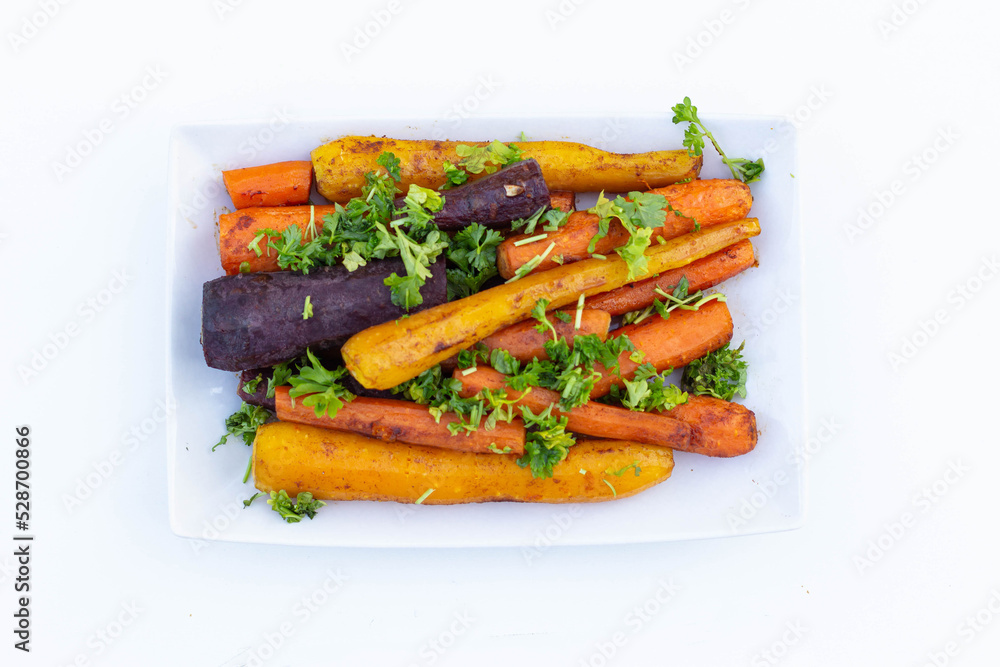 Baked multicolored carrots with parsley on a plate. View from above. Baked multicolored carrots with parsley on a plate. View from above.