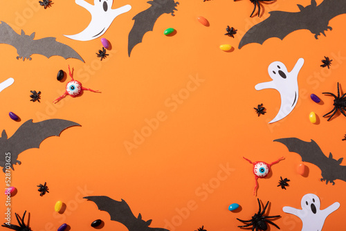 Multiple halloween toys and candies with copy space on orange background