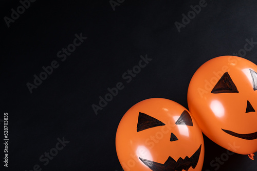 Two halloween pumpkin printed balloons with copy space on black background