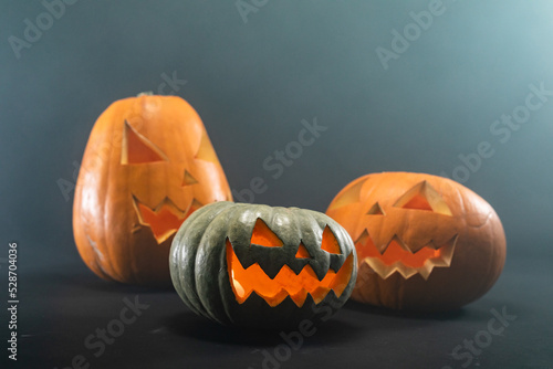 Close up view of three carved halloween pumpkin against black background