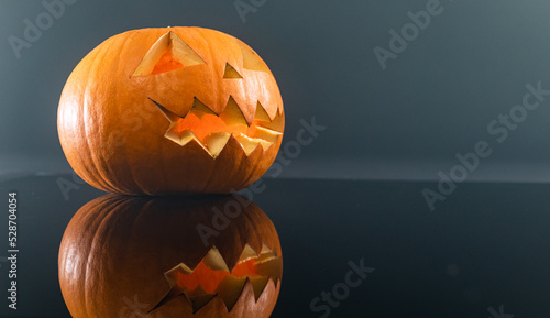 Close up of carved scary halloween pumpkin against grey background