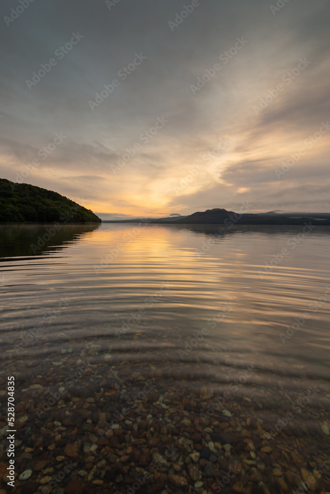 穏やかな夜明けの空と湖面の波紋。日本の北海道の屈斜路湖。